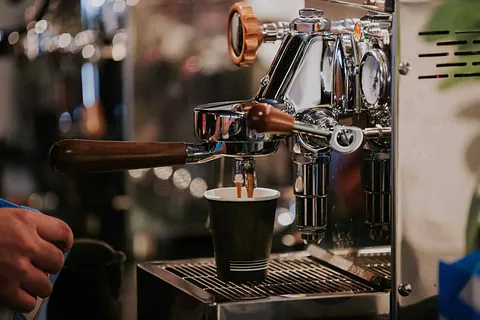 Mann venter på kaffe fra en kaffemaskin